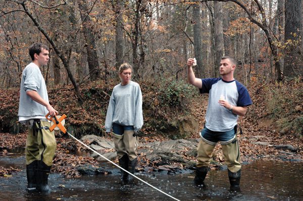 Civil engineering students standing in a creek working on a project