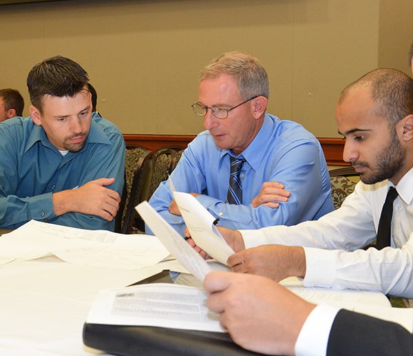 Professor and students sitting at a table looking at documents