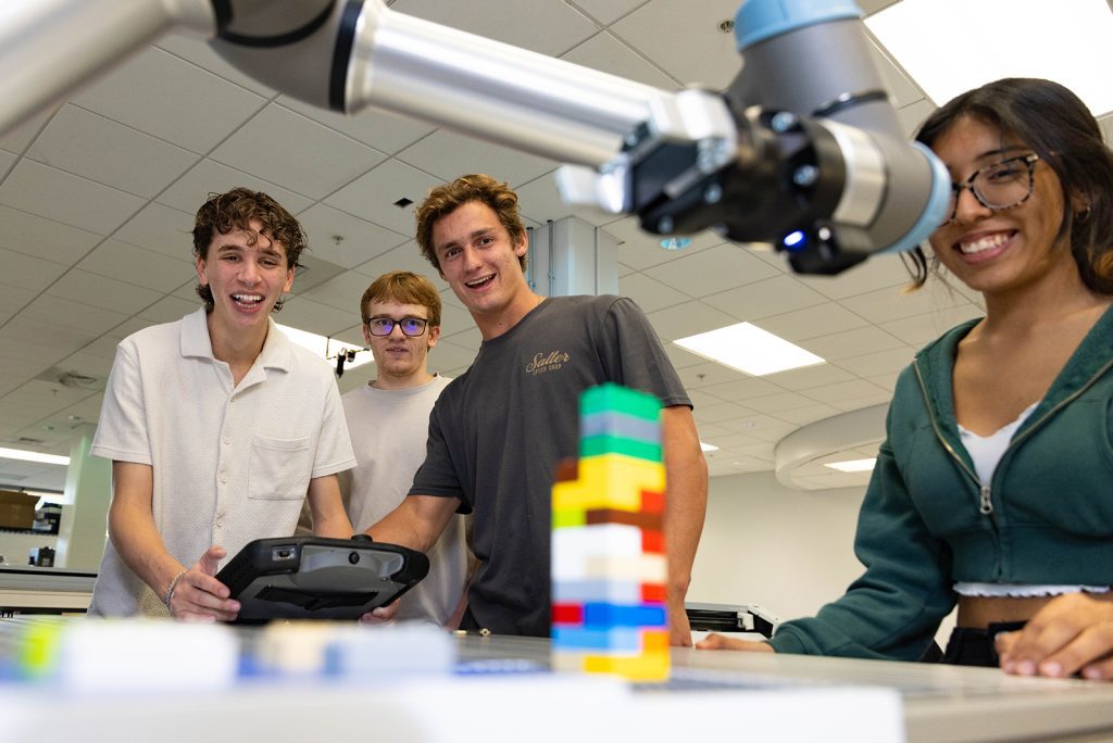 Students guide robotic arm to manipulate objects.